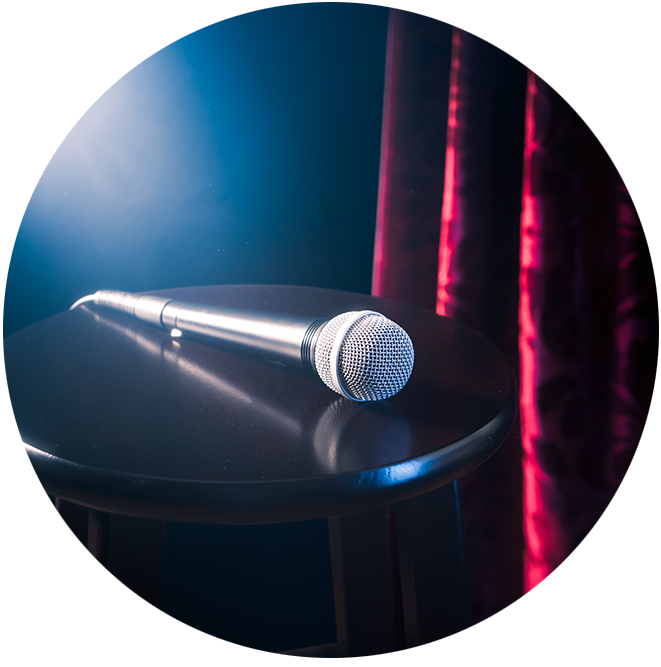 A microphone, lit by a theater spotlight, placed on a stool on stage
